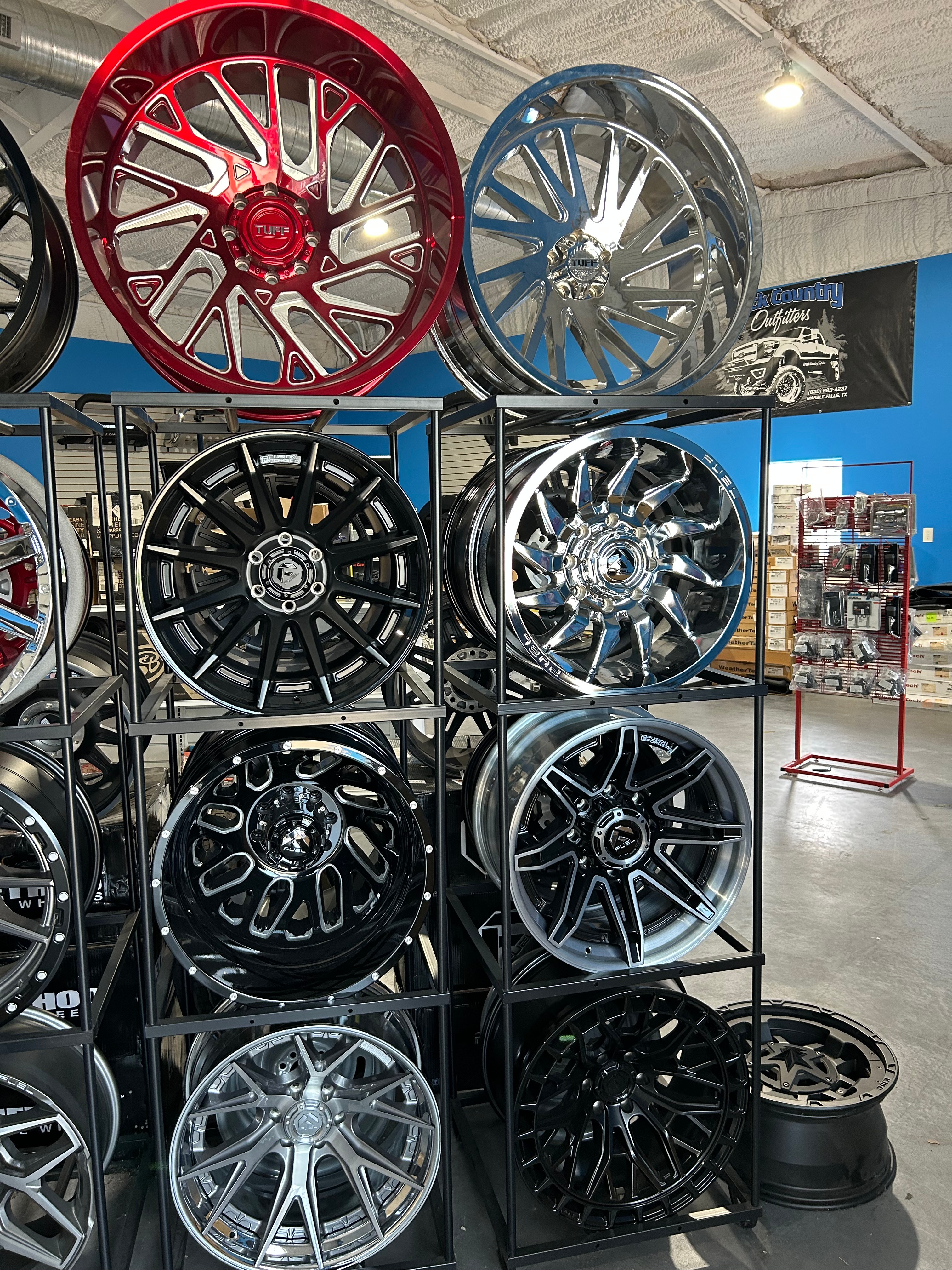 Custom truck wheel display wall featuring Tuff, Fuel, TIS, and chrome wheels — Truck Country Outfitters showroom