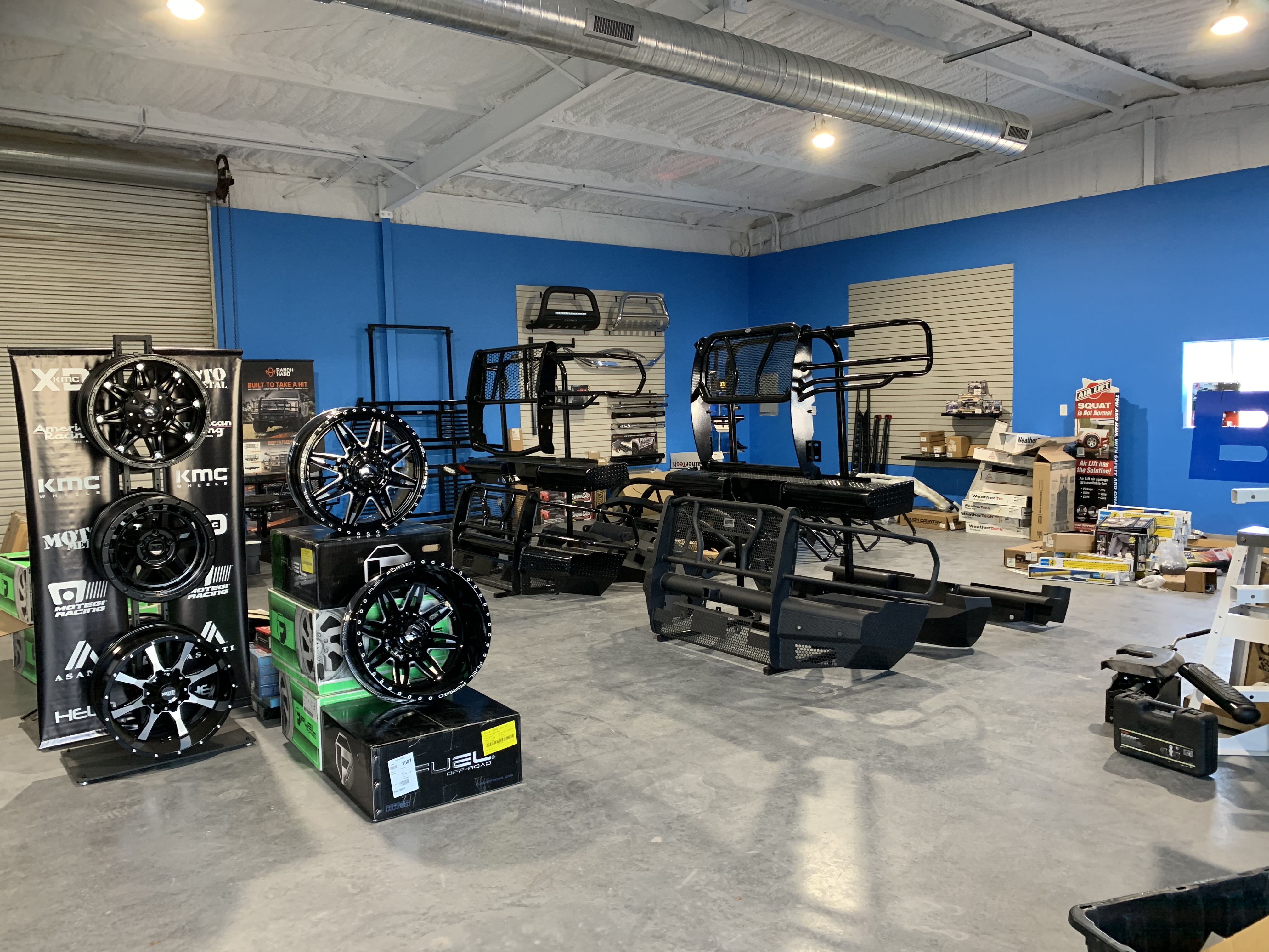 Truck Country Outfitters showroom interior — KMC, XD, Moto Metal, Asanti wheel displays alongside headache racks and bumpers