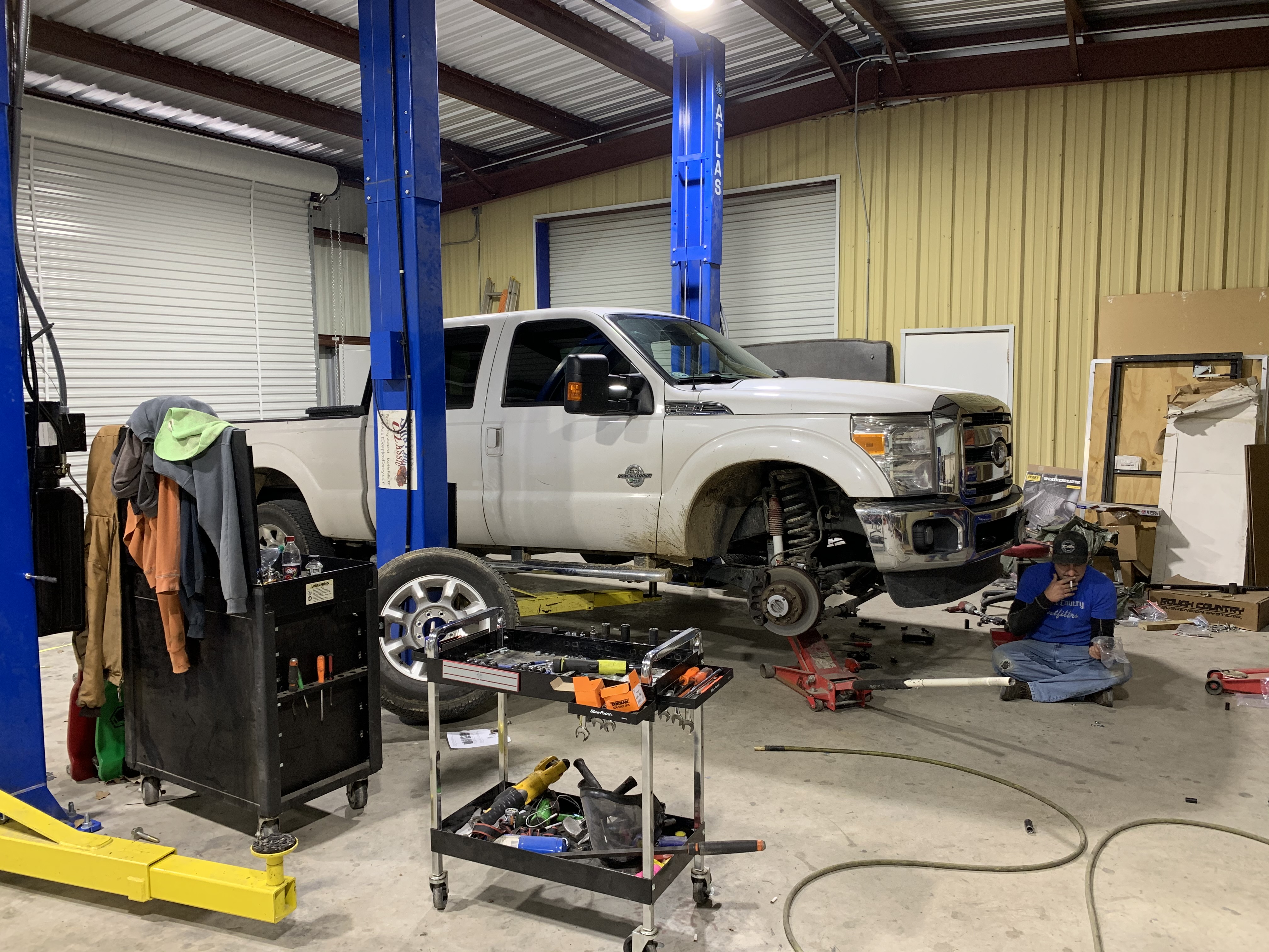Ford F-250 Super Duty on Atlas 2-post lift during suspension installation at Truck Country Outfitters, Marble Falls TX