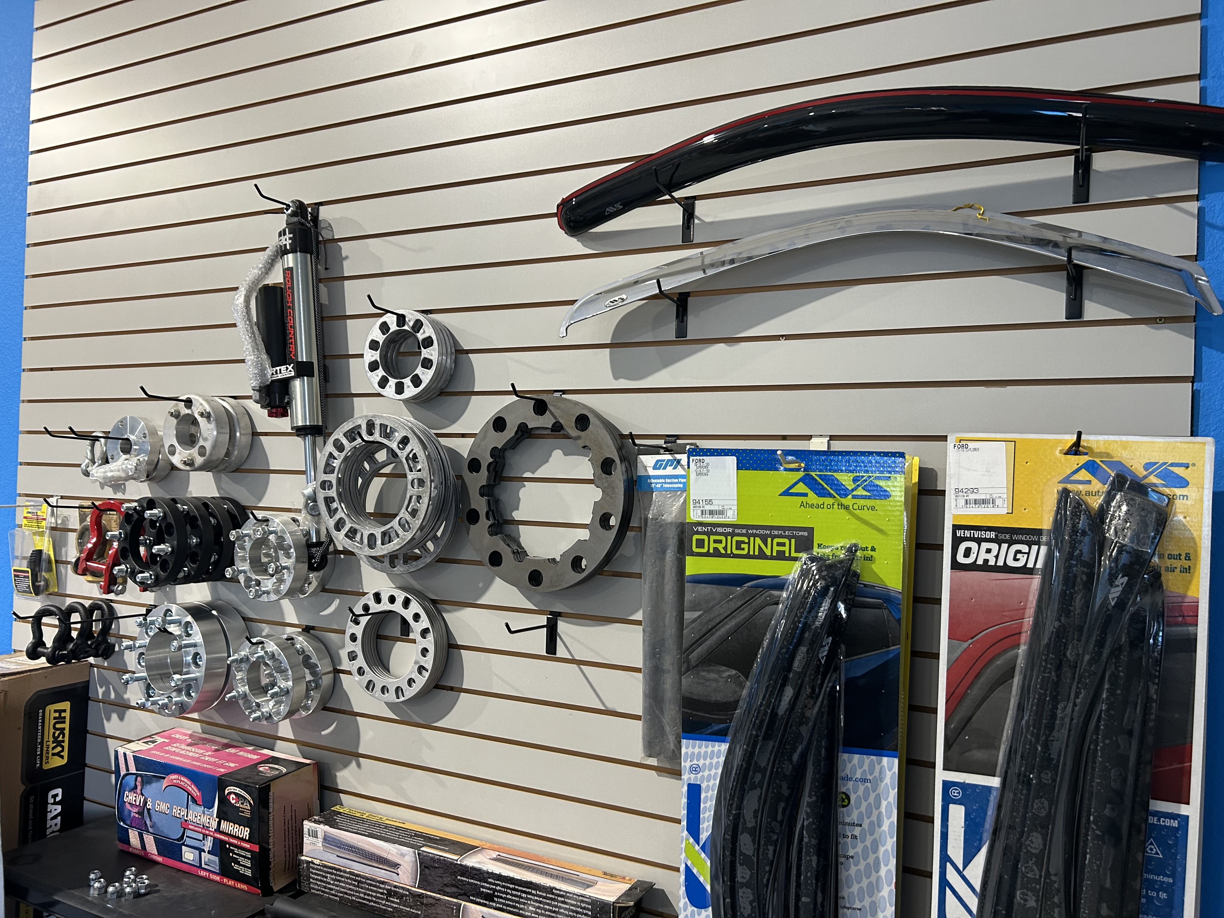 Truck accessories on slatwall including wheel spacers, AVS window deflectors, Tough Country shocks, and more