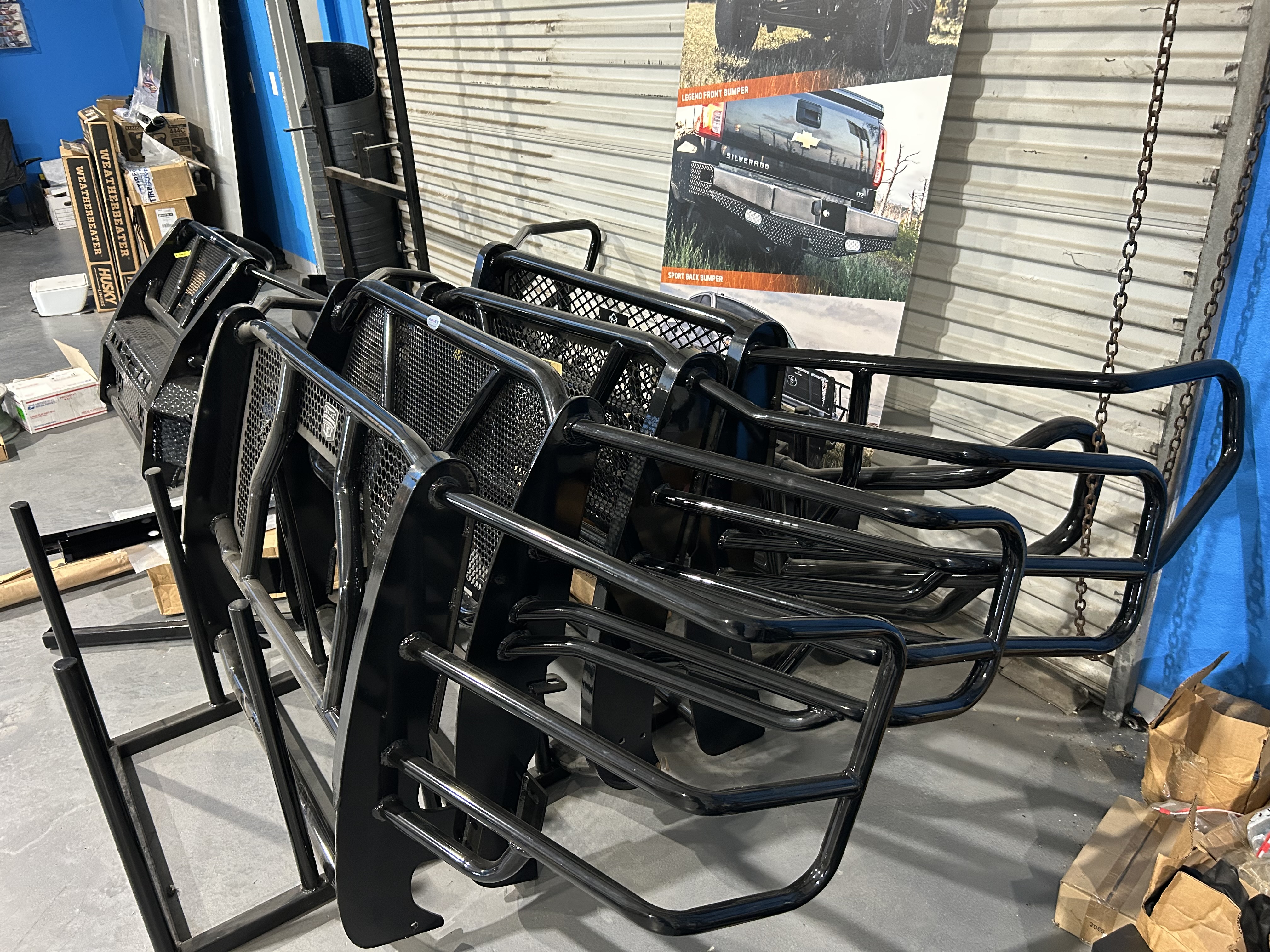 Multiple black steel grille guards and brush guards stacked in the Truck Country Outfitters shop
