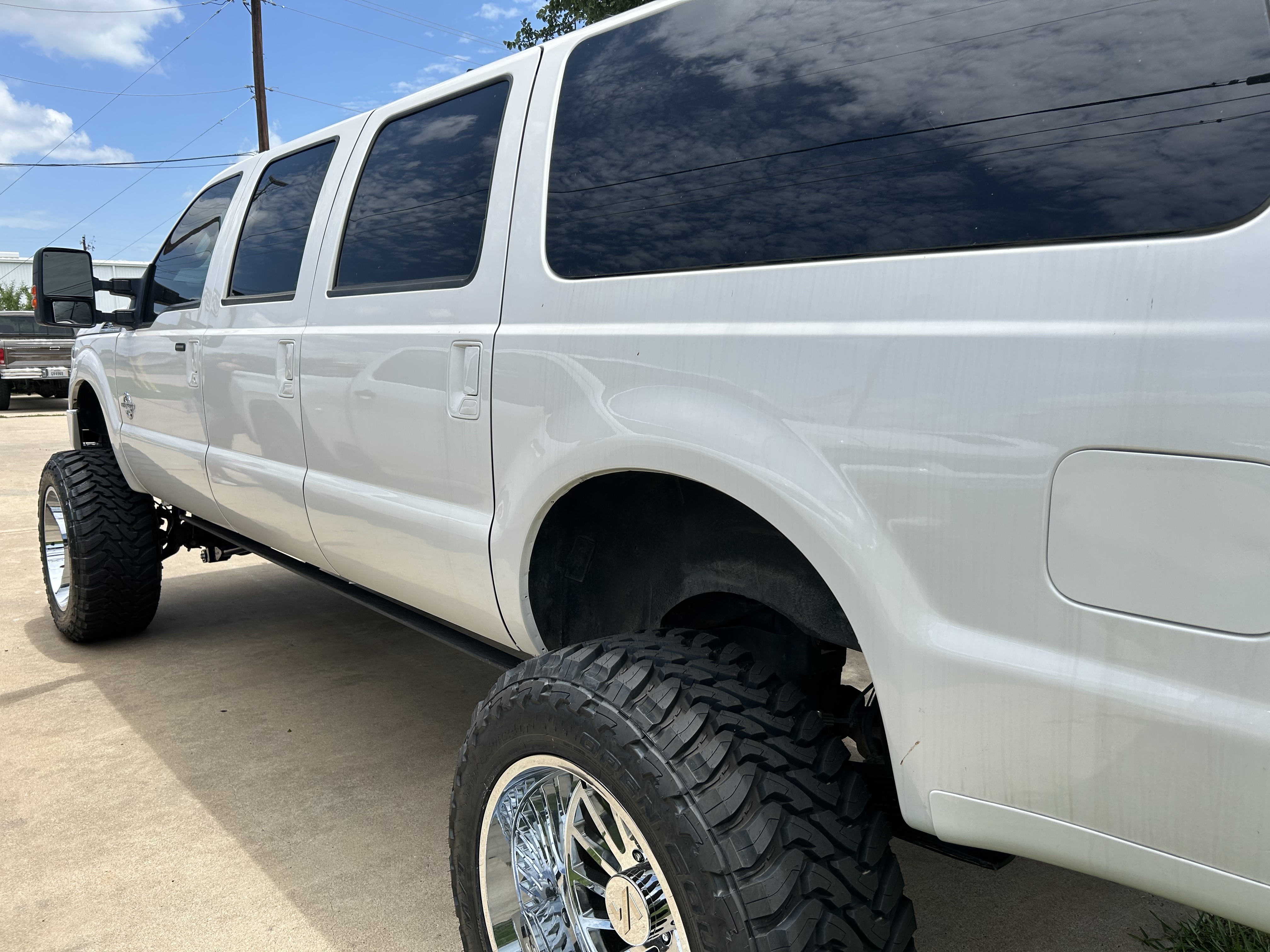 Lifted Ford Excursion with large suspension lift, chrome wheels, and mud terrain tires — Truck Country Outfitters, Marble Falls TX